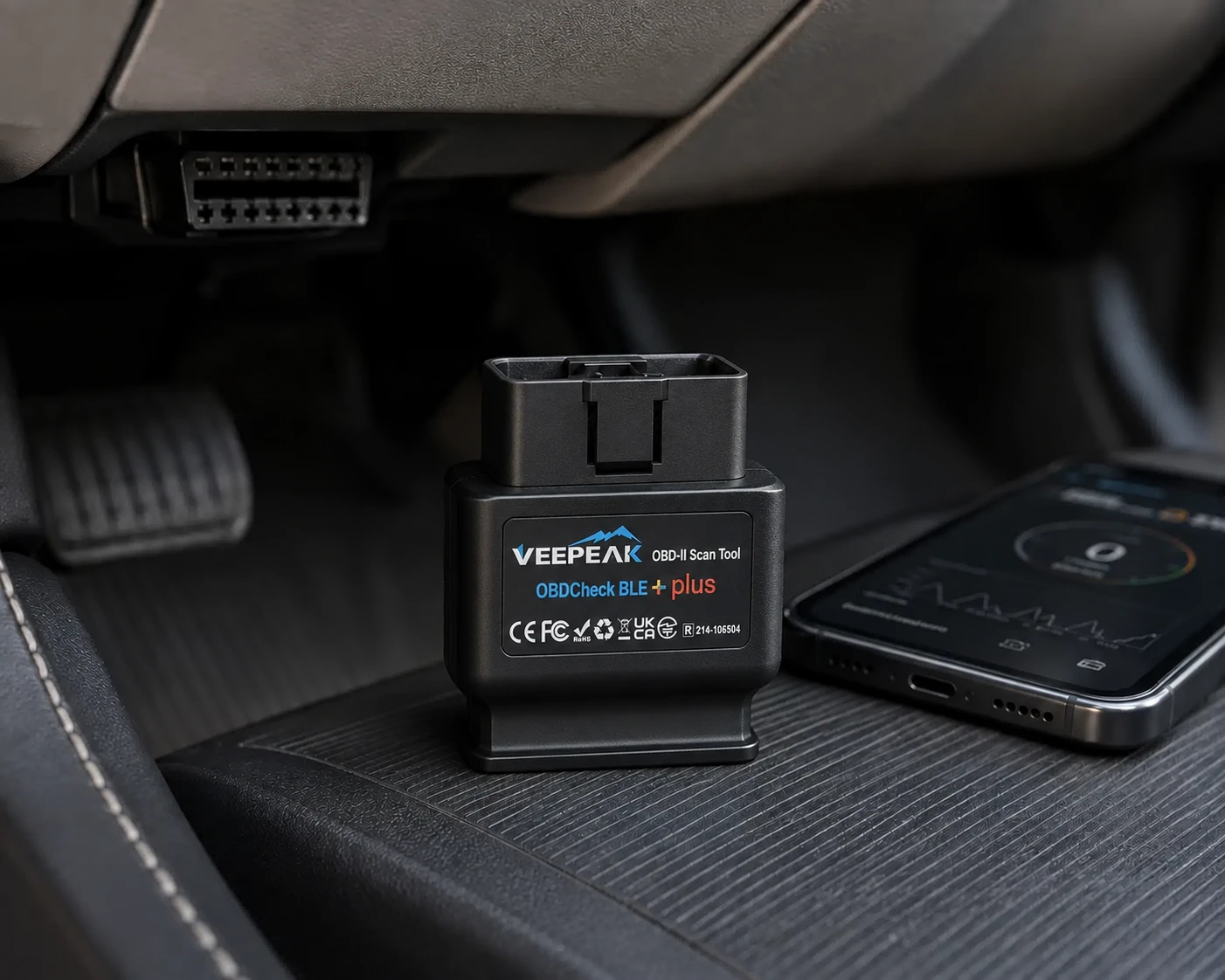 Veepeak OBDCheck BLE+ Plus Bluetooth OBD2 adapter plugged into a vehicle next to a phone