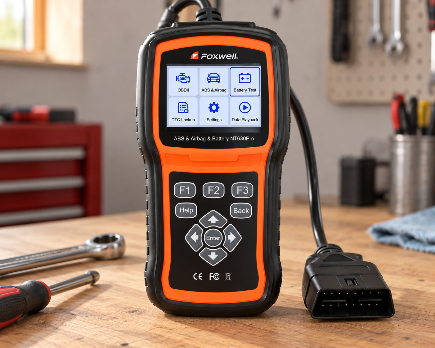 Foxwell NT630 Plus diagnostic scanner with OBD2 connector on a light wood automotive workshop bench