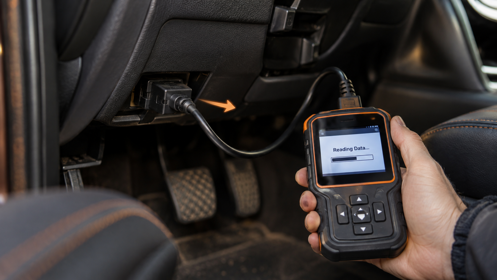 Handheld OBD2 scanner connected under the dashboard and displaying a reading data status during a standard diagnostic scan.
